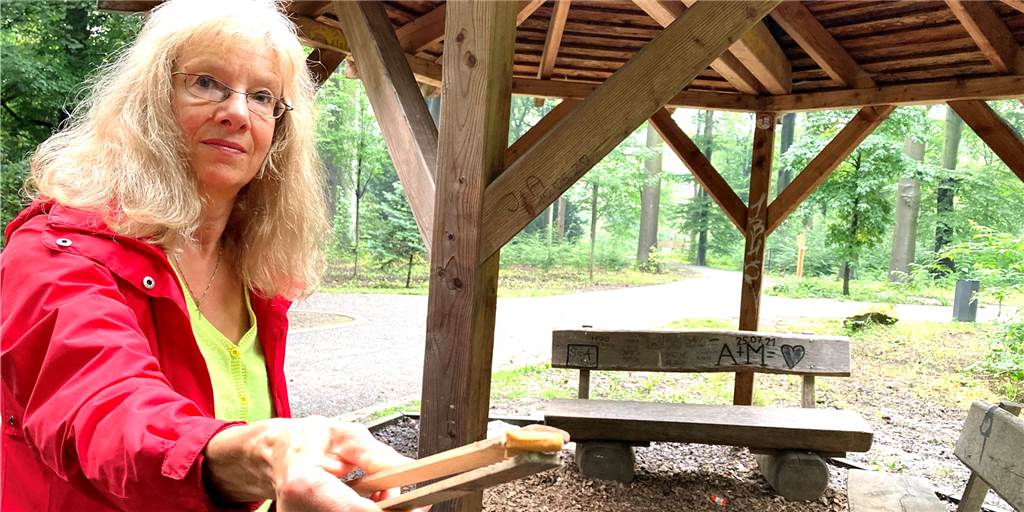 Müll im Rombergpark: „Sich ärgern bringt ja nichts, also sammle ich“ Anke Ulke vor einem Holzunterstand, von dessen Boden sie mit einer Holzzange einige Kippen einsammelt.