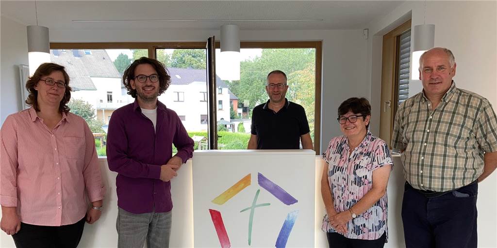 Fünf Kirchengemeinden im Westen teilen sich ein neues Büro Vor der ersten Öffnungszeit des neuen Büros: (v.l.) die Gemeindereferenten Martina Niedermaier und Bastian Lauf, Pfarrer Guido Hoernchen, Verwaltungsleiterin Barbara Werner und Hausmeister Jens Kowalke. In der Mitte hängt das bunte Logo des Pastoralverbunds Dortmunder Westen.