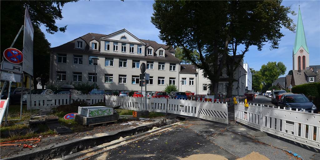 Neuer Gehweg im Westen ist fertig - und wird sofort wieder aufgerissen Vor dem Altbau der Regenbogen-Grundschule in Dortmund-Mengede ist der Gehweg schon wieder eine Baustelle. Der Neubau der Schule leuchtet weiß zwischen Altbau und Kirche.