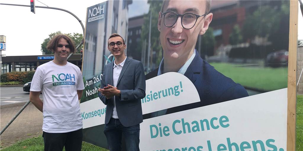 Der Dortmunder parteilose Bundestagskandidat Noah Trojanowski (r.) mit Vincent, einem Freund und Wahlkampfhelfer, vor seinem Großplakat an der B1.