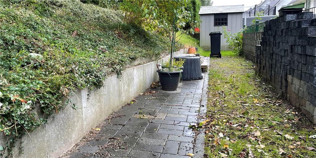 Hauseigentümer in Lünen müssen Gartenhäuser und Spieltürme entfernen Der gepflasterte Weg hinter dem Haus muss entfernt werden. Die Gartenhütte im Hintergrund muss voraussichtlich um etwa einen halben Meter versetzt werden.