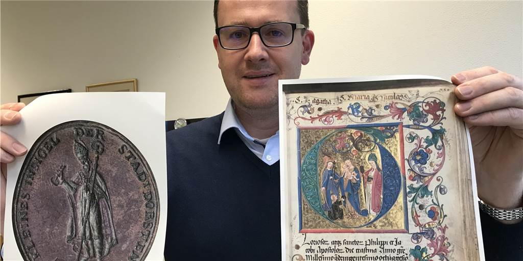 Auf der Spurensuche nach dem vergessenen Schutzpatron von Dorsten Der Dorstener Stadtarchivar Martin Köcher präsentiert ein Stadtsiegel mit dem Heiligee Nikolaus (links) und die Reproduktion des wertvollen Erfurter Rektoratsblatt von 1489 des aus Dorsten stammenden Professors Hermann Serges, auf dem auch die Dorstener Stadtpatrone Agatha und Nikolaus verewigt sind.