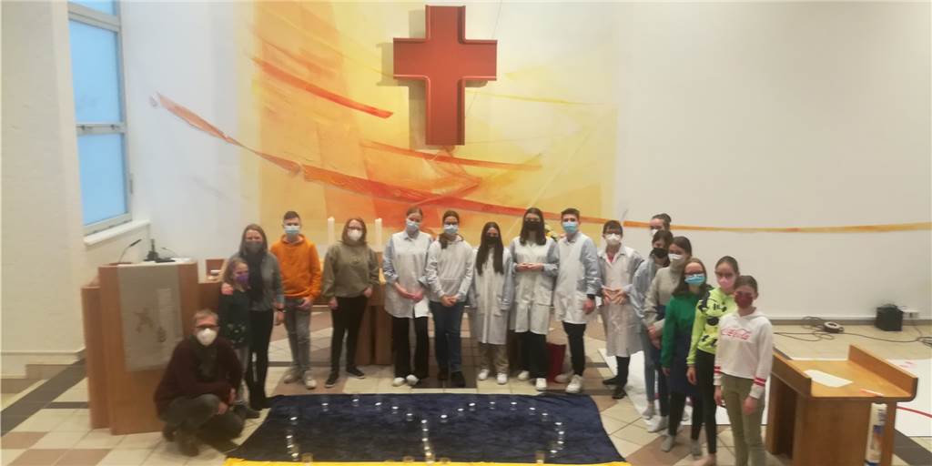 Kinder malen den Frieden: „Meine Oma hat Angst vor einem neuen Krieg“ Die Kinder des "Jugend-Stübchen" stehen vor einer großen gemalten Ukraine-Flagge mit einem Herz aus Kerzen.