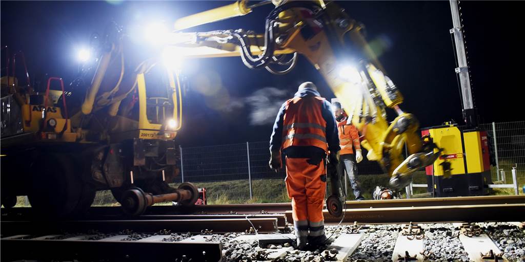 Mit Video und vielen Fotos: Echtes Schwergewicht auf dem Weg nach Asbeck Das Umladen der Drossel: Ein straßen- und schienenfähiger Bagger mit Kranarm hob die Schienen auf das Nebengleis, wo sie von Bahnmitarbeitern eingepasst und befestigt wurden.