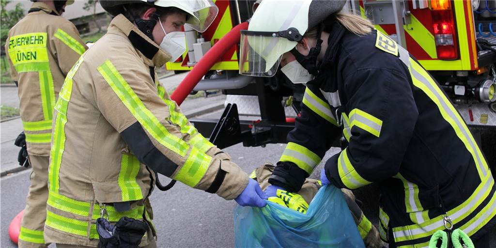 Rauch über Brambauer: Anwohner befürchten Schlimmes Feuerwehrleute verpacken die verschmutzte Einsatzkleidung nach dem Brand von Teerpappe in Brambauer in einen Sack.