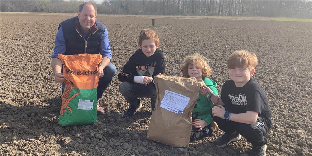 Mais oder Blühwiese: Landwirt Patrick Balster aus Selm sucht Blumenpaten Landwirt Patrick Balster mit der Maissaat. Ihm und seinen drei Neffen Leonard (v.l.n.r.), Fiete und Henry wäre aber die Blumenmischung im hellen Sack lieber.
