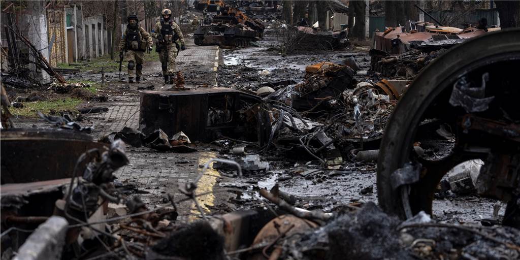Die Kriegsverbrechen von Butscha: Putins Truppen hinterlassen nur den Tod Zwei ukrainische Soldaten gehen auf einer Straße, die übersät ist mit zerstörten russischen Militärfahrzeugen. In der ukrainischen Stadt Butscha, 25 Kilometer nordwestlich der Hauptstadt Kiew, bietet sich nach dem Rückzug der russischen Armee ein Bild des Grauens.