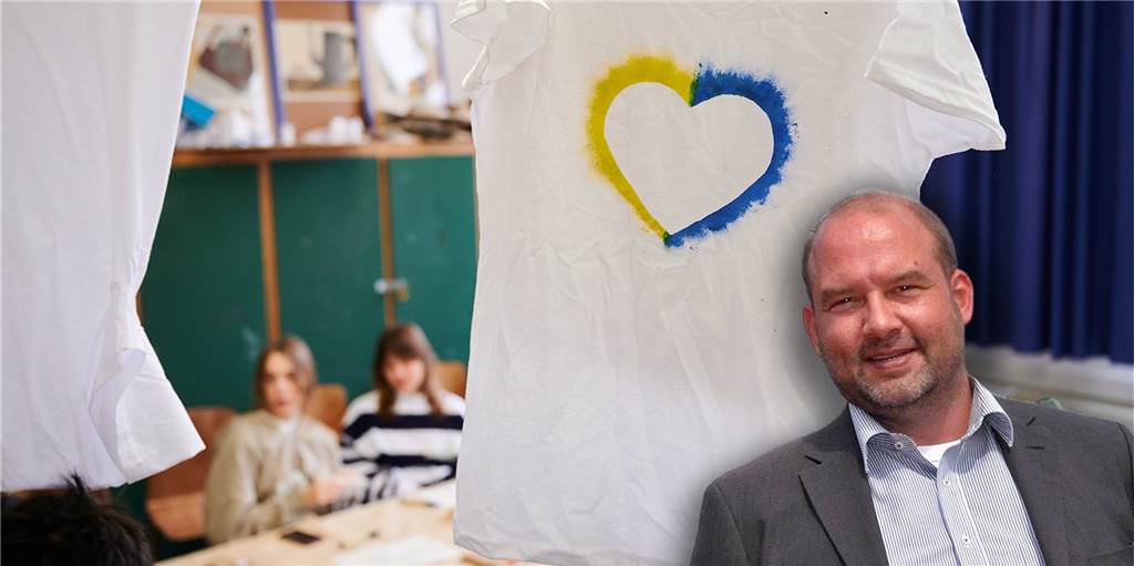 Ukrainische Schüler dürfen am Dorstener Petrinum in aller Ruhe ankommen Schulleiter Westhoff vor einem Herz-Symbol in den Farben der Ukraine.