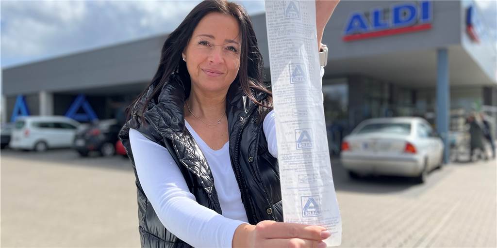 „Doppelt so teuer“ - Sandra Westerholt kauft gleiche Produkte vier Jahre später Sandra Westerholt hält einen langen Kassenbon in die Kamera. Sie steht vor dem Aldi.