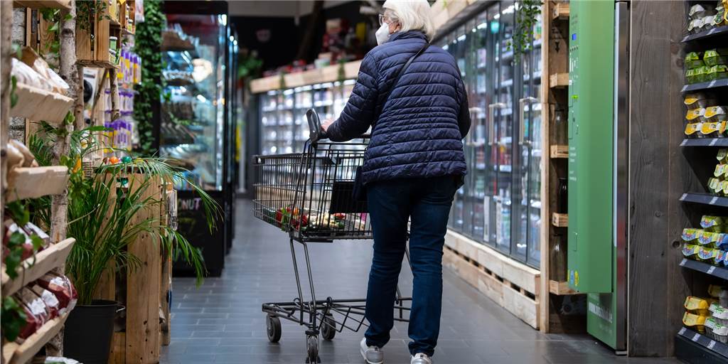 Steigende Lebensmittelpreise: So können Sie trotzdem günstig einkaufen Eine Frau geht mit ihrem Einkaufswagen durch einen Supermarkt.