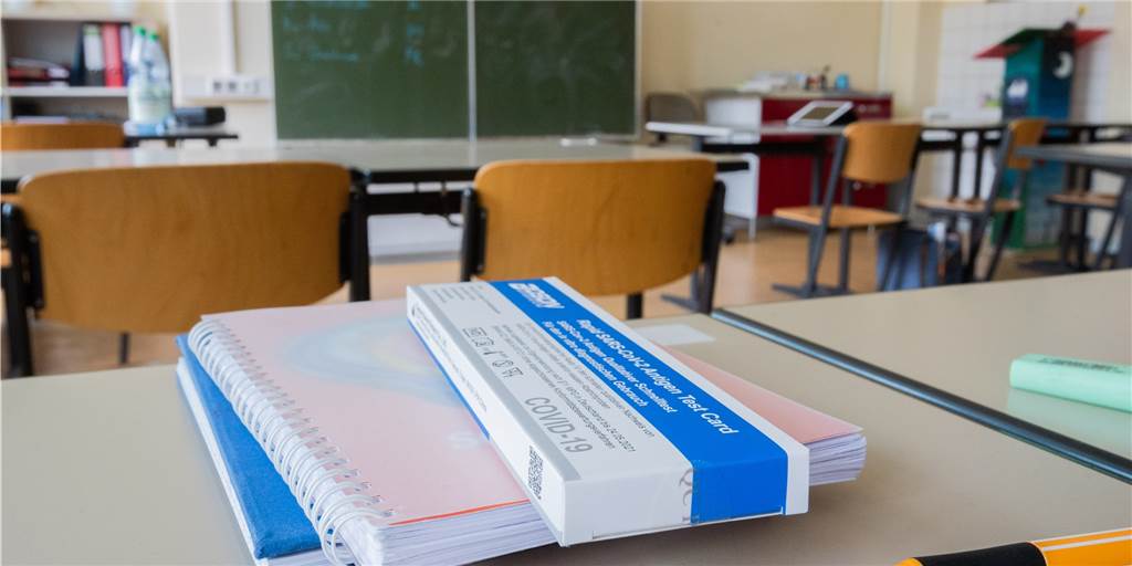 Test-Lagerung: Schulen haben klare Kommunikation verdient! Coronatest-Packung liegt auf einem Schulheft.