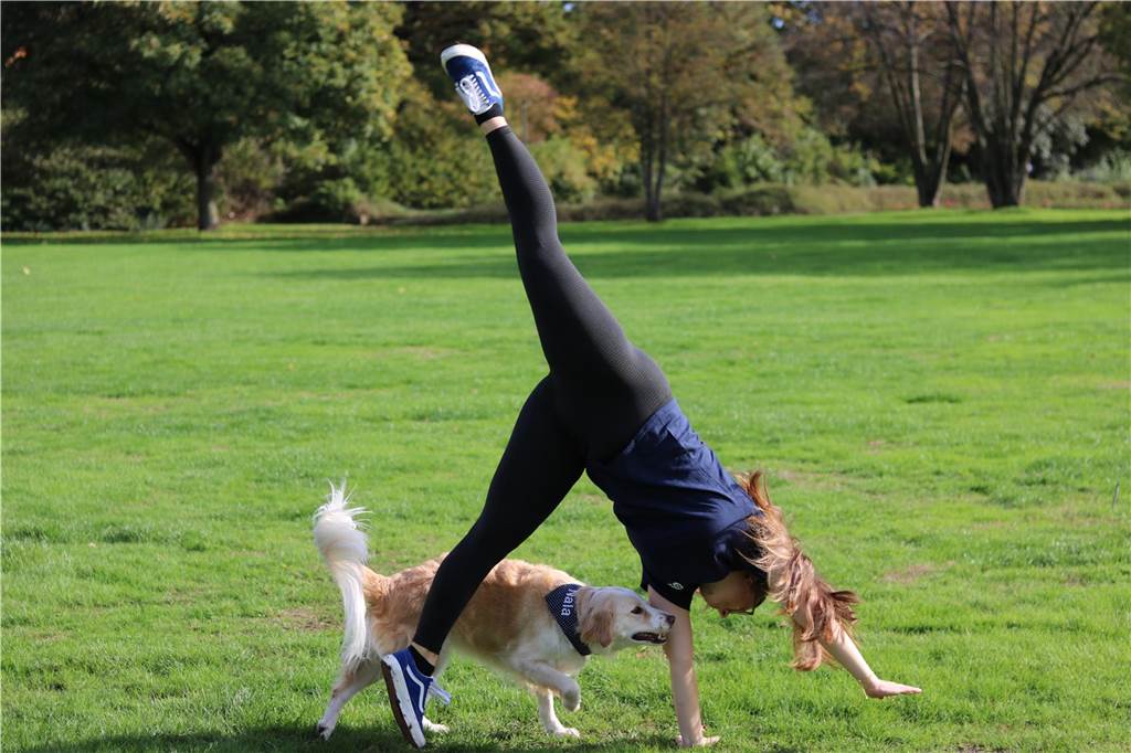 Guinness Buch der Rekorde: Frederike und Nala erfinden das Rad neu Frederike mach Radschläge auf einer Wiese, Hund Nala läuft durch Arme und Beine