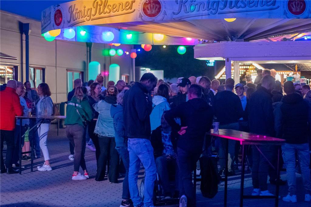 Viele Menschen vor einem bunt beleuchtetem Bierwagen.