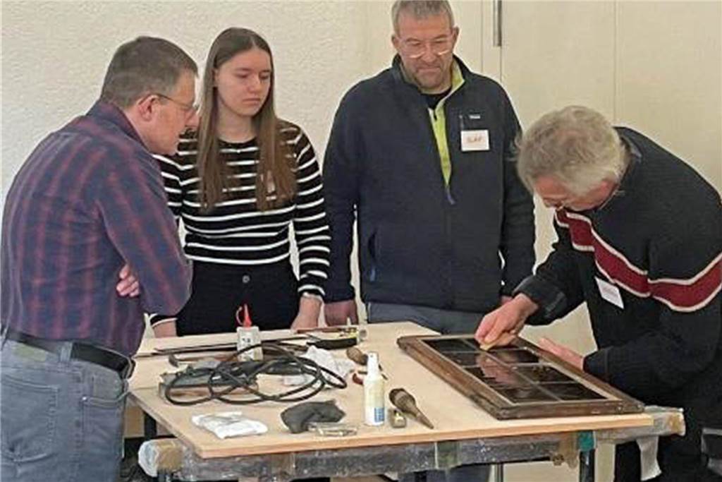 Menschen im Repair-Café von Werne tüfteln an einem Arbeitstisch.