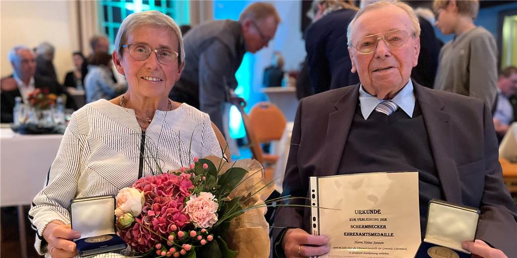 Vorbilder: Heinz Janzen (86) und Brigitte Straus (77) zeigten herausragendes Engagement Brigitte Straus und Heinz Janzen sitzen auf Stühlen und halten ihre Ehrenamtsmedaillen der Gemeinde Schermbeck in den Händen.
