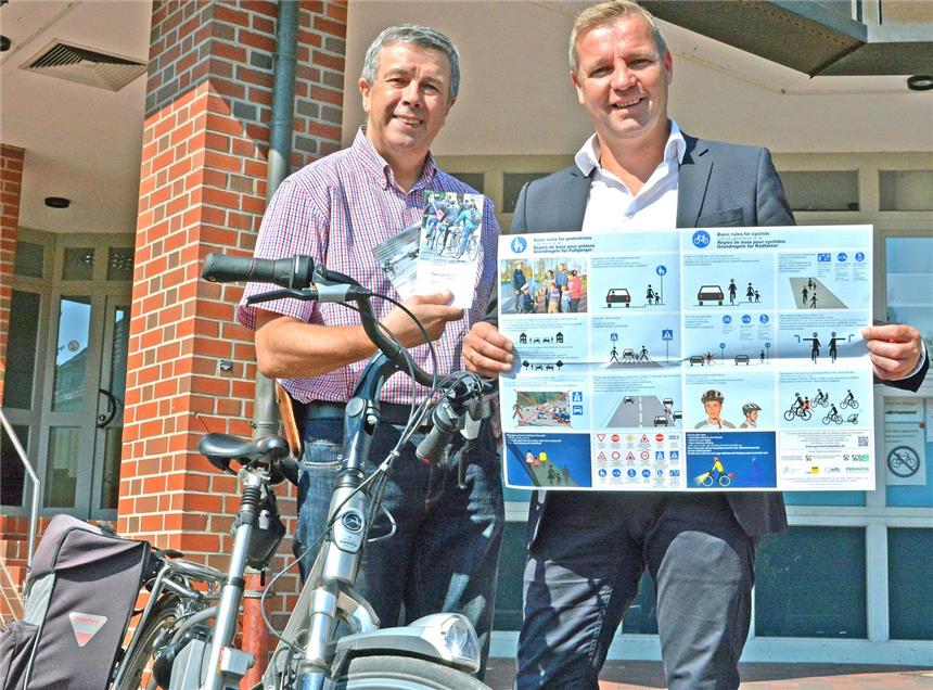 Broschüren, Handbücher und Poster in Deutsch, Englisch und Arabisch übergab Berthold Enning (l.), Schermbecker Bereichsleiter der Verkehrswacht Wesel, am Freitag an Bürgermeister Mike Rexforth. Verteilt wird das Infomaterial an Flüchtlinge der Gemeinde, die so die Grundregeln für Radfahrer im Straßenverkehr erlernen sollen.