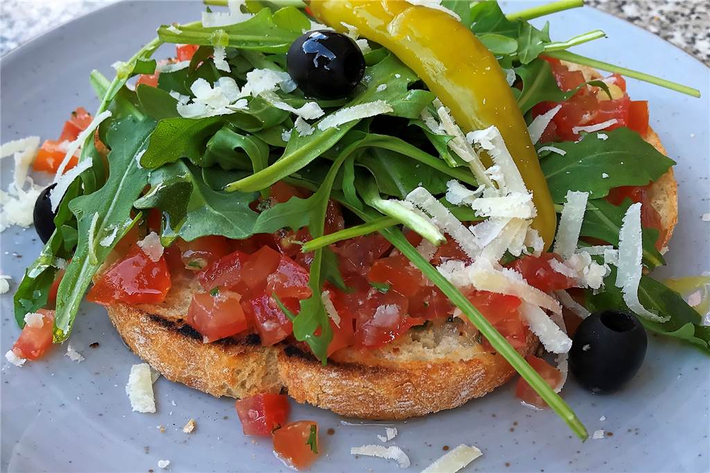 Bruschetta mit Tomaten, Knoblauch, Oliven und Peperoni.