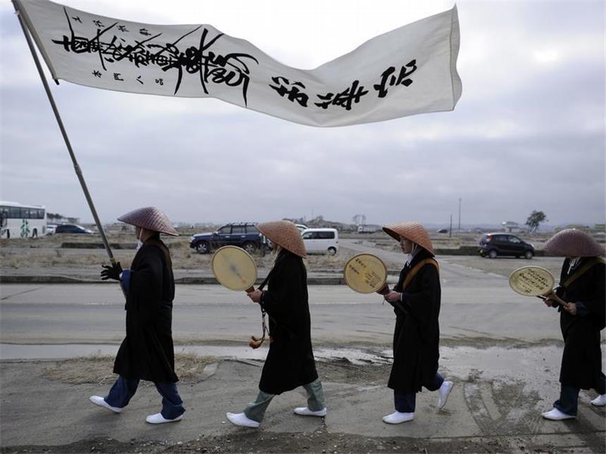 Japan und die Welt gedenken der Tsunami- und Atomtod-Opfer Buddhistische Mönchen bewegen sich betend durch ein vom Tsunami zerstörtes Gebiet. Foto: Franck Robichon