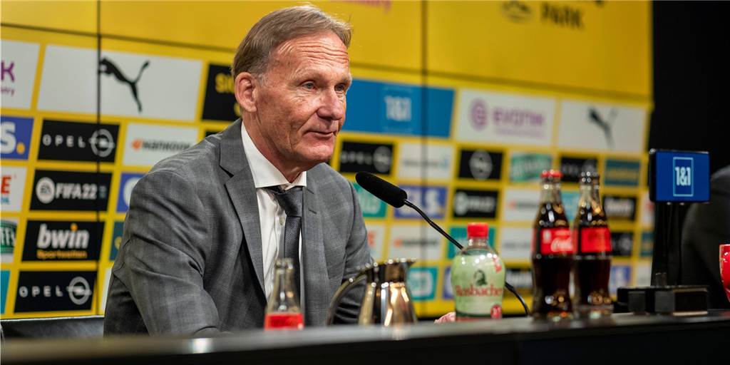 Geschäftsbericht: BVB erwartet Gewinn - Änderung bei Spielergehältern geplant Hans-Joachim Watze sitzt auf einer Pressekonferenz vor einem Mikro.