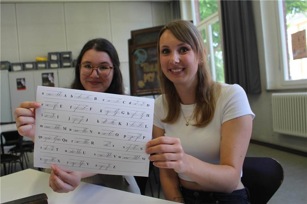Marion Rabe lässt ein altes Familien-Buch entziffern und wird überrascht Charlotte Herzog (l.) und Rabea Kern, ihre Nachfolgerin als studentische Hilfskraft, kennen sich mit alter Schreibschrift aus. Sie halten einen Zettel mit alten Schriftzeichen in die Kamera.