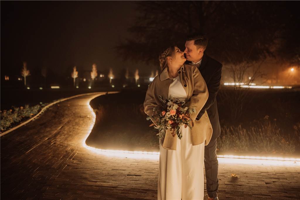 Kira und Matthias Portleroi sind die „Schlossvermählten des Jahres“ Chiara und Daniel Milsom-Van de Löcht aus Raesfeld stehen im Dunkeln vor einer beleuchteten Wiese.