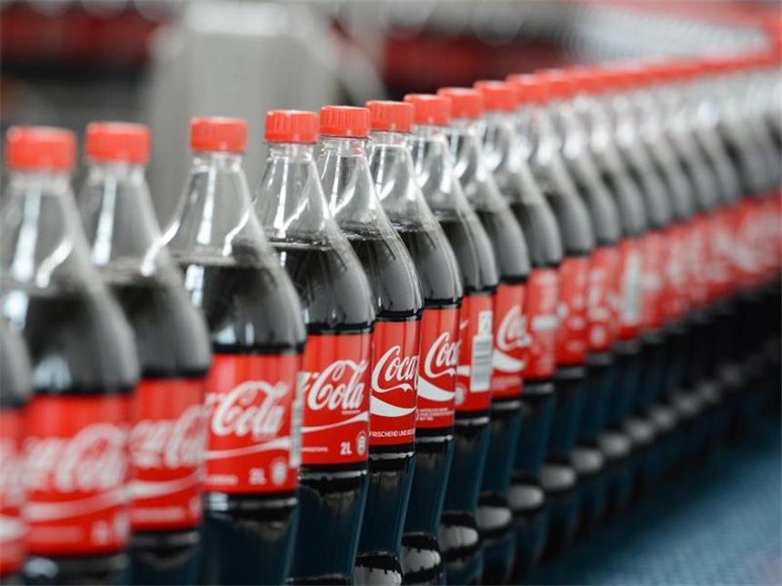 Coca-Cola verdient deutlich weniger Coca-Cola-Flaschen auf einem Transportband. Foto: Jens Kalaene/Illustration