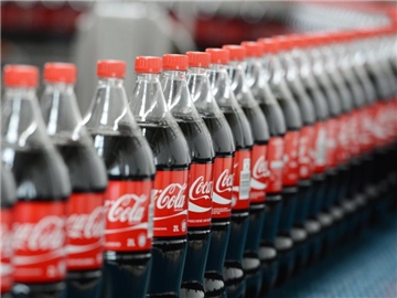 Coca-Cola-Flaschen auf einem Transportband. Foto: Jens Kalaene/Illustration
