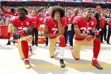 Colin Kaepernick (M), Eli Harold (l) und Eric Reid von den San Francisco 49ers knien beim Abspielen der Hymne. Foto: John G Mabanglo/AP