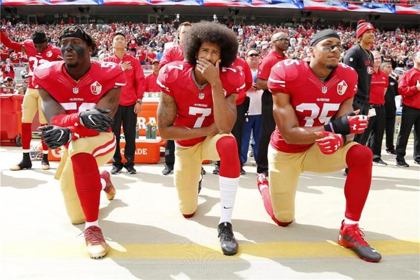 Colin Kaepernick (M.), und seine Mannschaftskameraden Eli Harold (l.) und Eric Reid knien beim Abspielen der Nationalhymne, um gegen die behandlung von Minderheiten in den USA zu protestieren. Foto: John G Mabanglo
