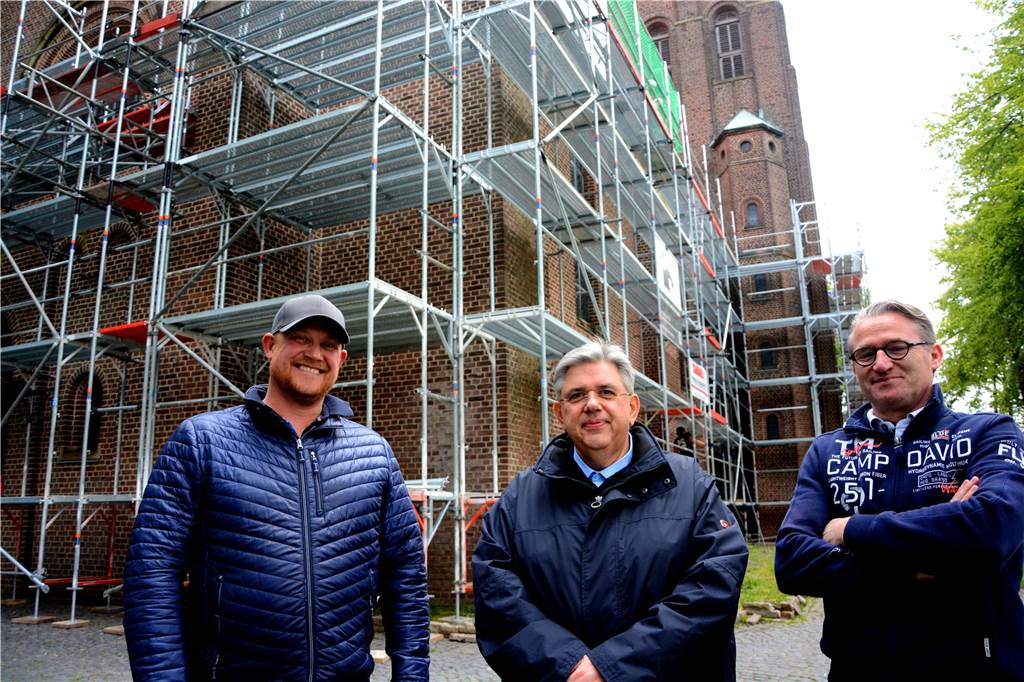 Ein Besuch in schwindelnder Höhe auf dem Baugerüst an der St. Jakobuskirche Dachdeckermeister Michael Hayk, Pfarrer Stephan Scho und Matthias Pohl, Geschäftsführer des Gerüstbauunternehmens (v.l.), freuen sich auf die Sanierung. Der Pfarrer, weil die Kirche renoviert wird, die beiden Handwerker, weil die Arbeiten an der Kirche eine echte Herausforderung sind.