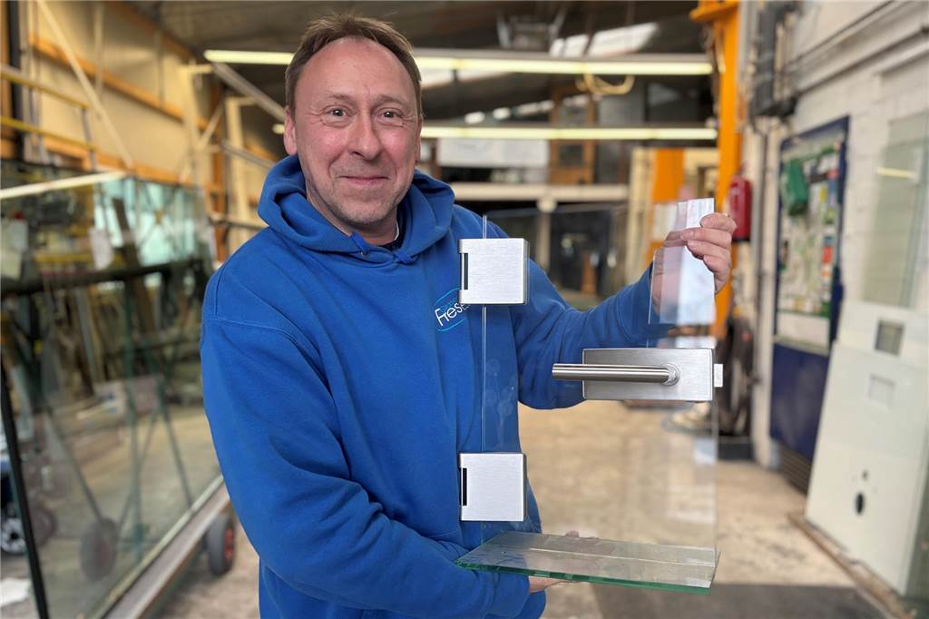 Oliver Frese steht in der Produktionshalle und hält das Miniatur-Modell einer Tür in den Händen..