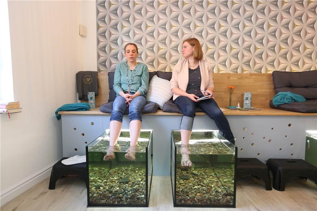 Doch keine Geschäftsaufgabe: Neuer Inhaber bei Olfener Fish-Lounge Zwei Frauen halten ihre Füße in die Aquarien mit Fischen
