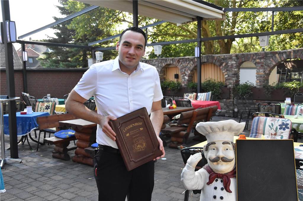 So reagieren Gastronomen auf die Erhöhung der Mehrwertsteuer ab 2024 Danilo Djeric steht im Biergarten des Steakhaus Lindenhof mit einer Speisekarte.