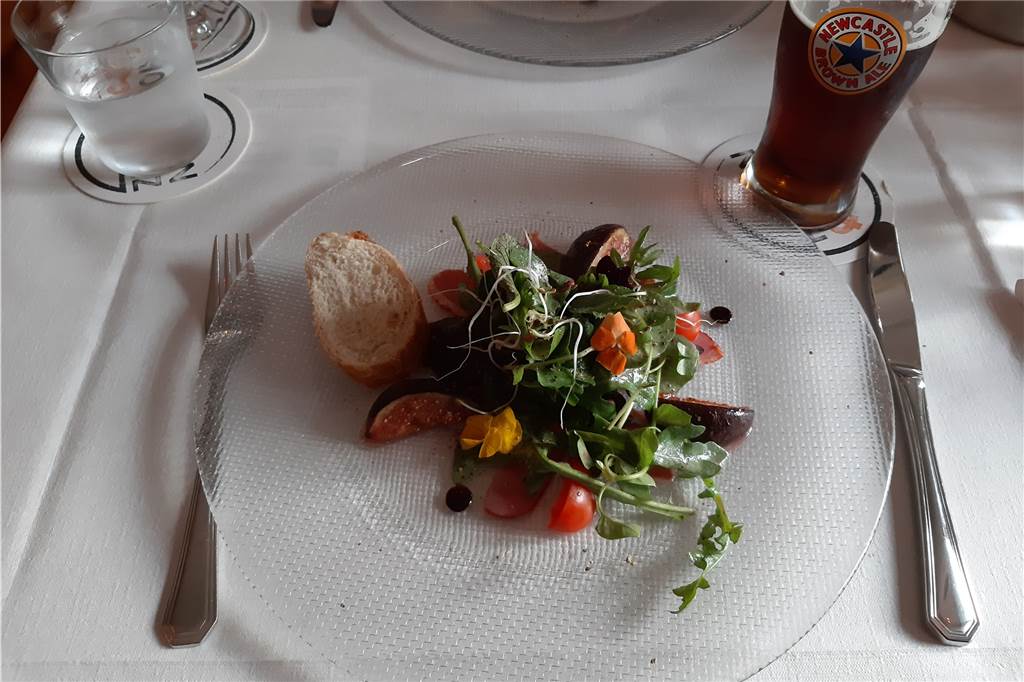 Das Amuse-Gueule: Geräucherte Entenbrust an Wildkräutersalat mit Cider-Granatapfeldressing und flambierten Feigen. 