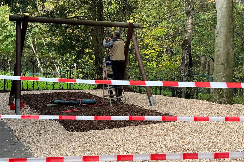 Glückspilze haben Übergangs-Quartier mitten in der Natur gefunden Ein Spielgerät auf dem Außengelände ist mit einem Band abgesperrt. Ein Mann repariert das Gerät.