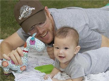 Das Baby Carmen Santos-Lake und ihr Vater spielen in Bangkok auf einer Decke. Der Amerikaner Gordon Lake und sein Partner, Spanier Manuel Santos, kämpfen in Thailand um ihr Baby, das von einer Leihmutter ausgetragen wurde. Foto: dpa