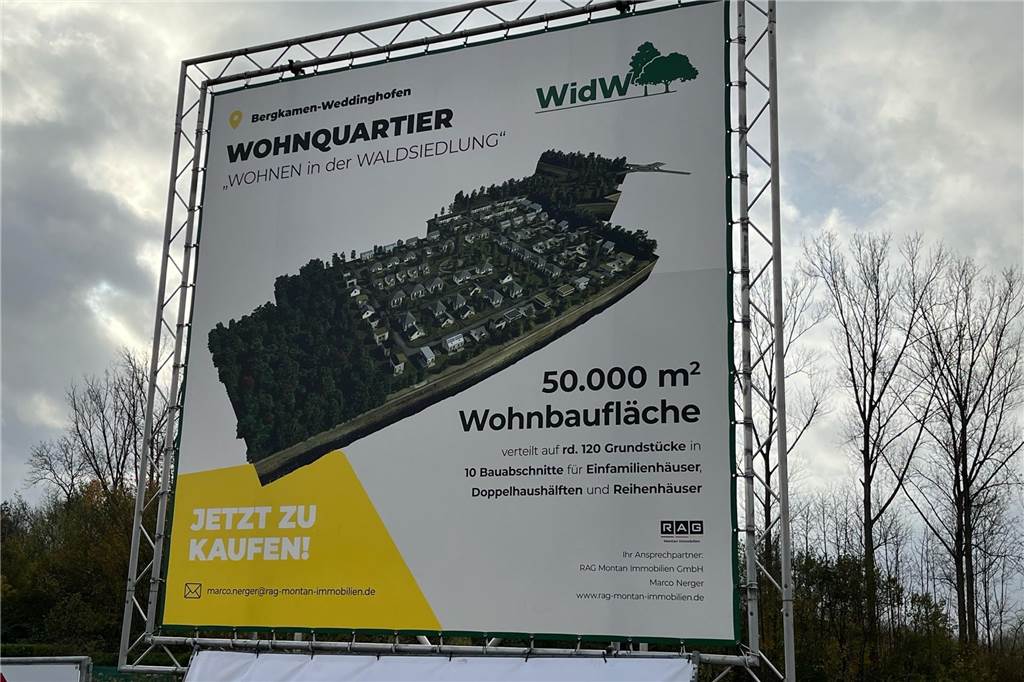 Waldsiedlung auf Grimberg 3/4: RAG MI vermarktet die Baugrundstücke An der Zufahrt zur Waldsiedlung steht ein Bauschild mit einer Computersimulation, wie die Siedlung aussehen soll und Informationen für Interessenten.