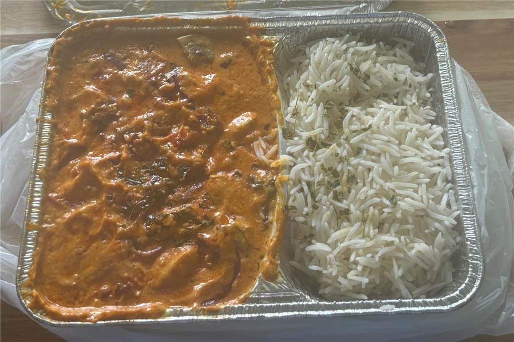 Zwischen Pizza und indischen Speisen: Il Rustico überzeugt im Test In einem Alu-Behälter ist links ein Hähnchen mit Sauce und auf der rechten Seite Reis.