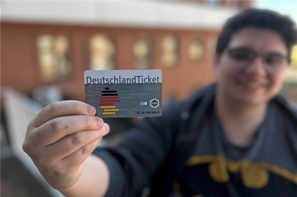 Eine dunkelhaarige Frau hält mit der rechten Hand ihr Deutschlandticket.