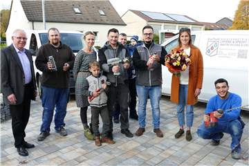 Das erfolgreiche erste Jahr in Schwerte feierten (v.l.): Mitarbeiter Bastian Fifielski, Katharina und Konstantin Specht mit Sohn Anton, Mitarbeiter Artur Handurdye (hinten), Jim Liffers und seine Verlobte Alina Krause sowie Auszubildender Mohammed Karout, sowie Volker Stein (l., Geschäftsstellenleiter Unna der Kreishandwerkerschaft Hellweg-Lippe).