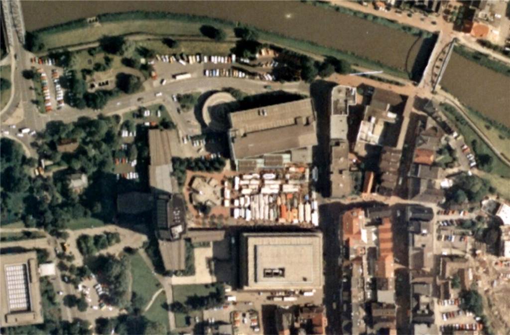 An den Marktplatz angrenzend steht wieder ein Gebäude. Parkplätze wurden gebaut, die Straßen sind asphaltiert. 