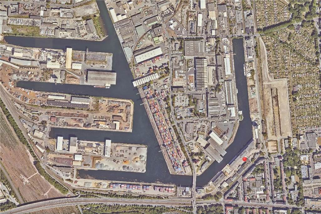 Das Foto aus dem Jahr 2022 entstand ein Jahr vor der Fertigstellung der Akademie für Theater und Digitalität. Die sechste Sparte des Theater Dortmund hat mit Beginn der Spielzeit 2023/2024 in einem neues Gebäude am Hafen, Speicherstraße 17, ihre Arbeit aufgenommen: ein Labor für internationale Künstlerinnen und Künstler, die dort mit 3D-gedruckten Kostümen, künstlicher Intelligenz und anderen neuen Techniken experimentieren. Der Neubau liegt direkt neben dem 2023 eingeweihten Heimathafen.