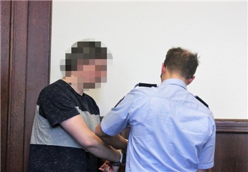 Das Foto zeigt den wegen Mordes vorbestraften Angeklagten beim Abnehmen der Handschellen.
 