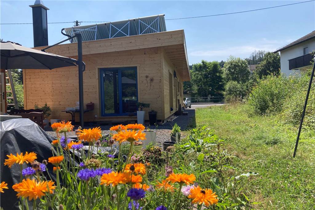 Ulrike und Otto Szillat und ihr Traum vom (fast) autarken Haus Ein Holzhaus steht in einem naturbelassenen Garten, auf dem Dach ist eine Solarthermie-Anlage montiert.,