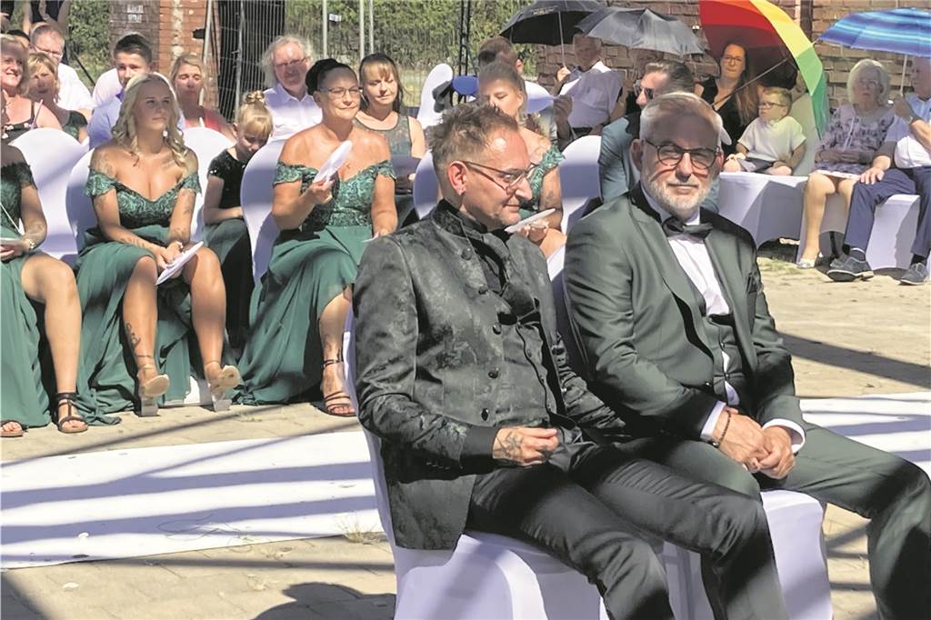 „Willkommen in meinem Leben“: Maik und Andreas heiraten auf Schlägel & Eisen in Herten Das Hochzeitspaar lauscht den Worten der Rednerin, die die Zeremonie unter dem roten Förderturm gestaltet.