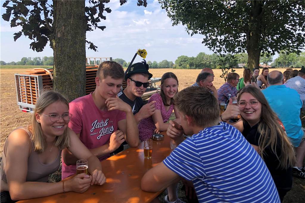 Junge Menschen sitzen beim Schützenfest im Freien an einem Tisch.
