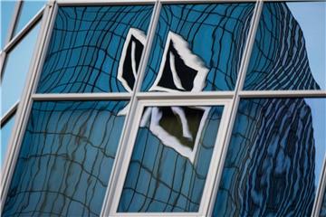 Das Logo der Deutschen Bank spiegelt sich verzerrt in einer Hochhausfassade. Foto: Andreas Arnold