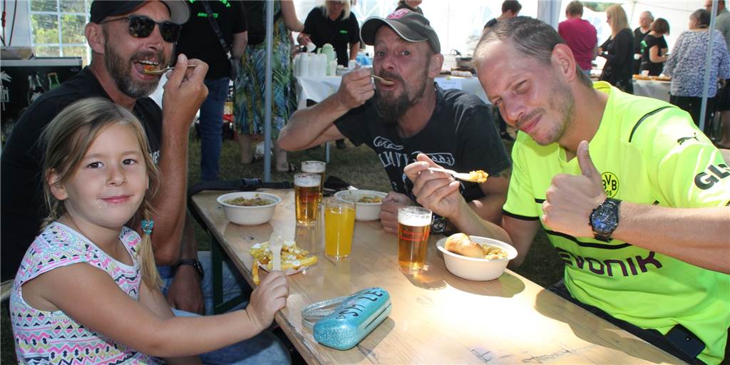 Familienspaß, Bergbau und Erbsensuppe: So war das Kanalfest 2022 Drei Männer und ein Mädchen sitzen beim Kanalfest an einem Tisch und essen Erbensuppe oder Pommes.