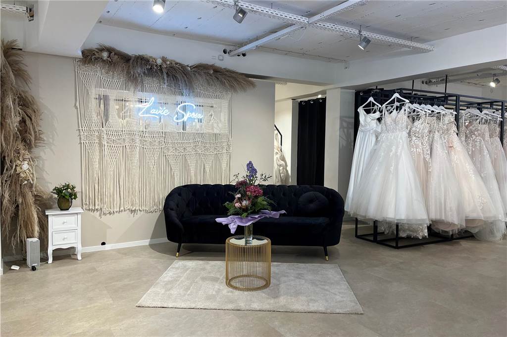 Brautkleider statt Möbel: „Lavie Sposa“ feiert Neu-Eröffnung nach Umzug Blick in ein Brautmodengeschäft: Es ist in neutralen Farben – in Weiß, Beige oder Elfenbein – gehalten. Als Deko dienen Trockenblumen, goldene Elemente und Samtsofas.