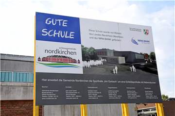 Das Plakat auf dem Parkplatz vor der alten Turnhalle zeigt, wie der Neubau später aussehen soll. Bald soll die Sporthalle eröffnet werden.